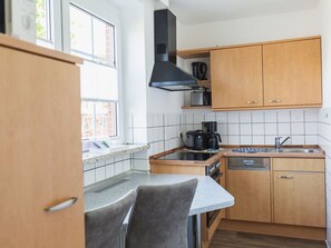 A compact kitchen with a stove, coffee maker, and a dishwasher. - Holiday Apartments Haus Bärbel Duhnen Apartment '1' (Cuxhaven)
