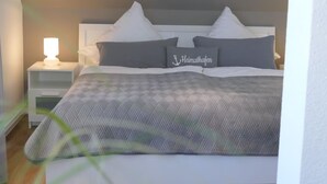 A neatly made bed with a grey and white checkered bedspread, two pillows, and a bedside lamp.