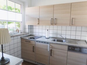 Una cucina moderna con mobili chiari in legno, un lavello in acciaio inossidabile e una lavastoviglie integrata.