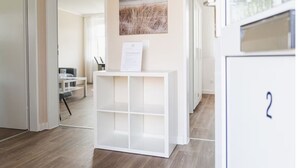 Un couloir avec un comptoir d’accueil, une œuvre d’art encadrée au mur et une porte portant un numéro.