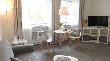 Un salon moderne comprenant un canapé, une table basse, un meuble pour la télévision et un coin repas avec des chaises et une table.