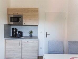 A compact kitchenette with a microwave, coffee maker, and a small potted plant.