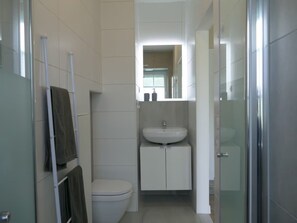 Une salle de bain avec des toilettes blanches, un lavabo et un miroir au-dessus.