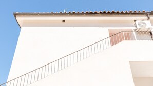 A white building with a metal staircase and a tiled roof. - Room 'Monte Suso' with sea view, shared terrace and air conditioning (Montallegro)