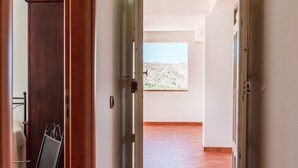 An open door leading to a room with a tiled floor, a metal chair, and a view of a desert landscape. - Room 'Monte Suso' with sea view, shared terrace and air conditioning (Montallegro)