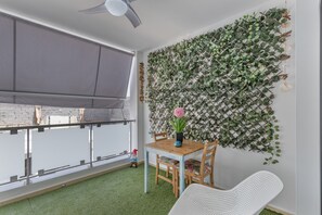 A balcony with a view, a table with chairs, and a wall-mounted plant.