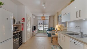 A modern kitchen with white cabinets, a dishwasher, and a dining area with a table and chairs.