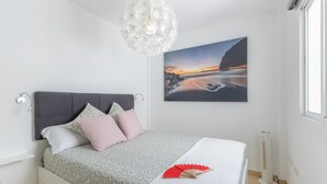 A bedroom with a bed, a wall-mounted picture, a ceiling light fixture, and a radiator.