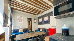 A modern kitchen with a wooden ceiling, a dining area with a table and chairs, a red refrigerator, and a large vase. - UrbanFlat 44 - Pretty 2 Bedroom Flat in Paris near metro station (París)