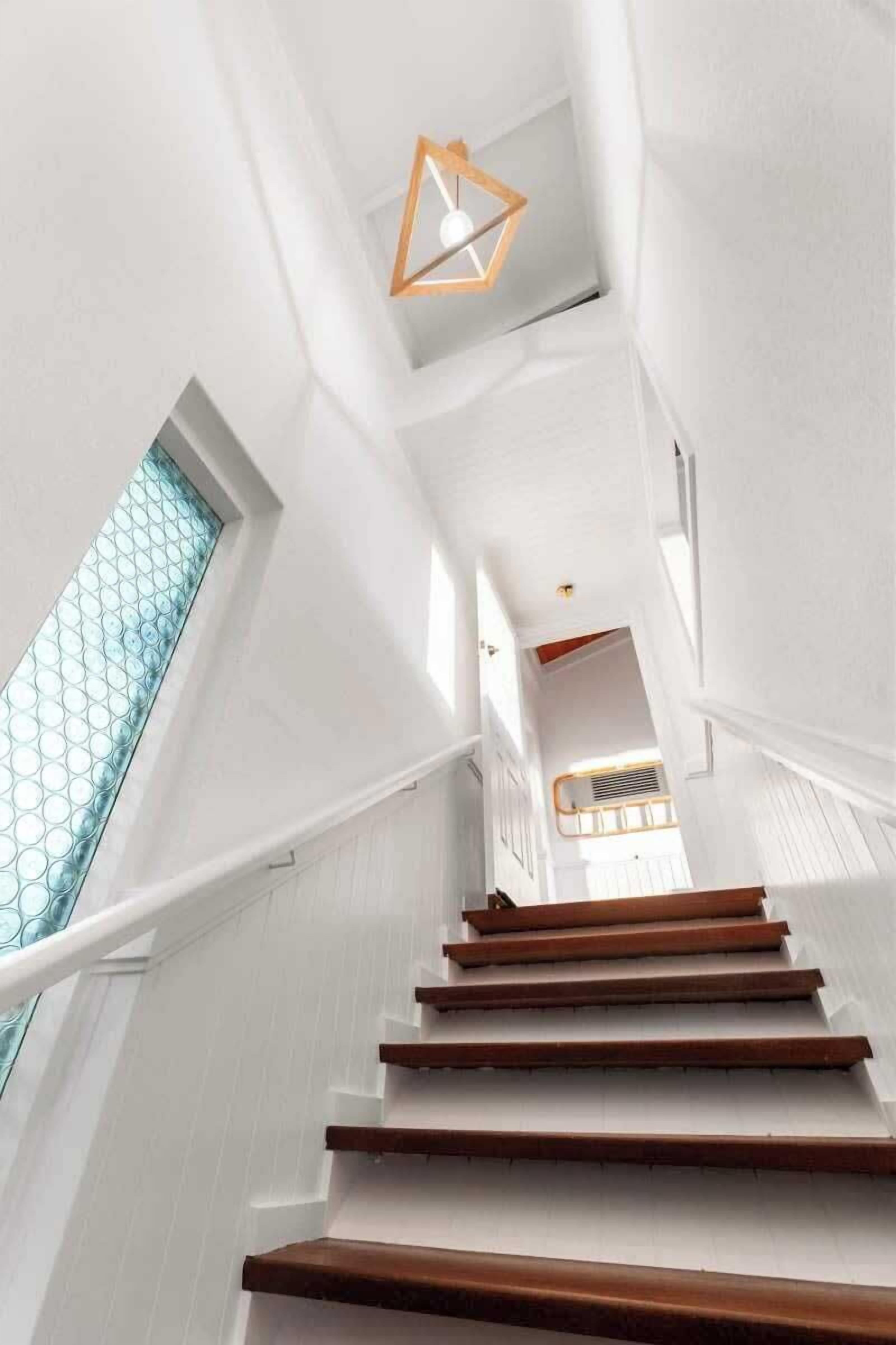Un escalier aux murs blancs et aux marches en bois menant vers le haut.