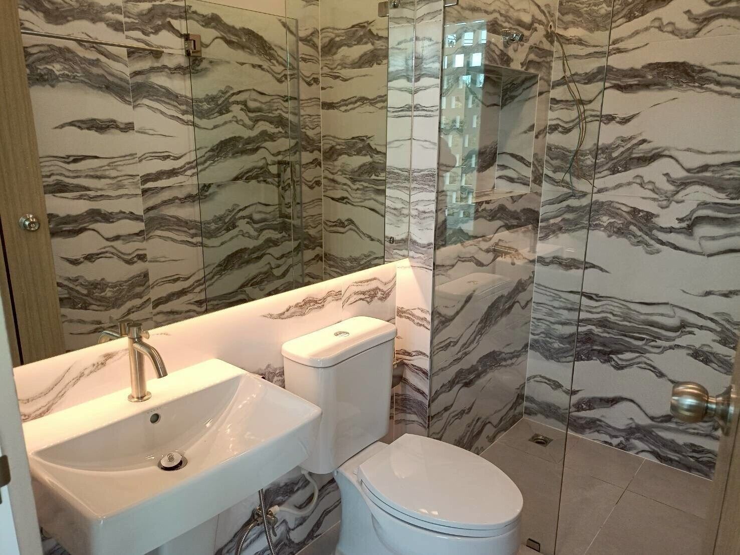 A bathroom with marble-patterned walls, a white sink, and a toilet.