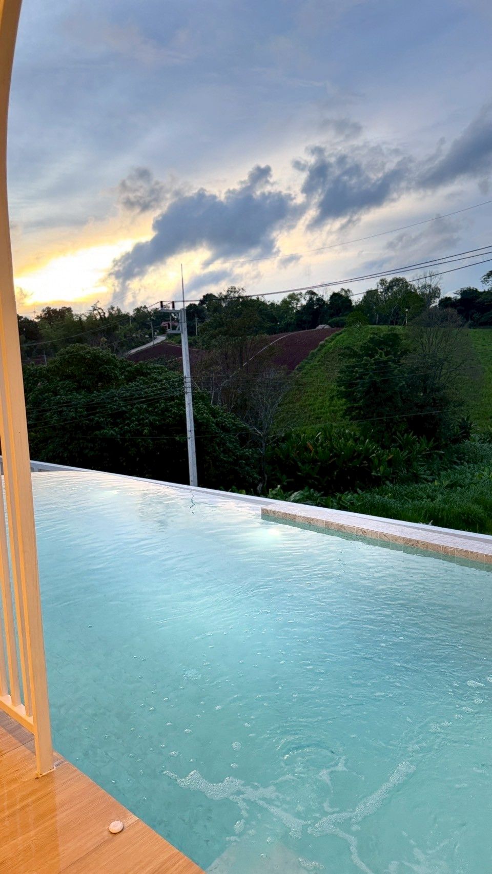 A swimming pool with a clear view of the surrounding landscape and a cloudy sky.