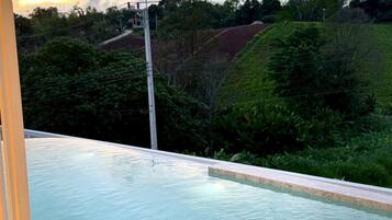 A swimming pool with a clear view of the surrounding landscape and a cloudy sky.