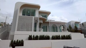 Un edificio moderno con varios balcones, ventanas amplias y fachada blanca.