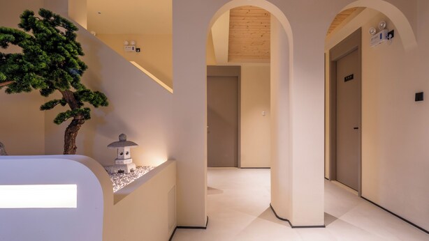 Un interior moderno con una escalera, techo de madera y un árbol en maceta.
