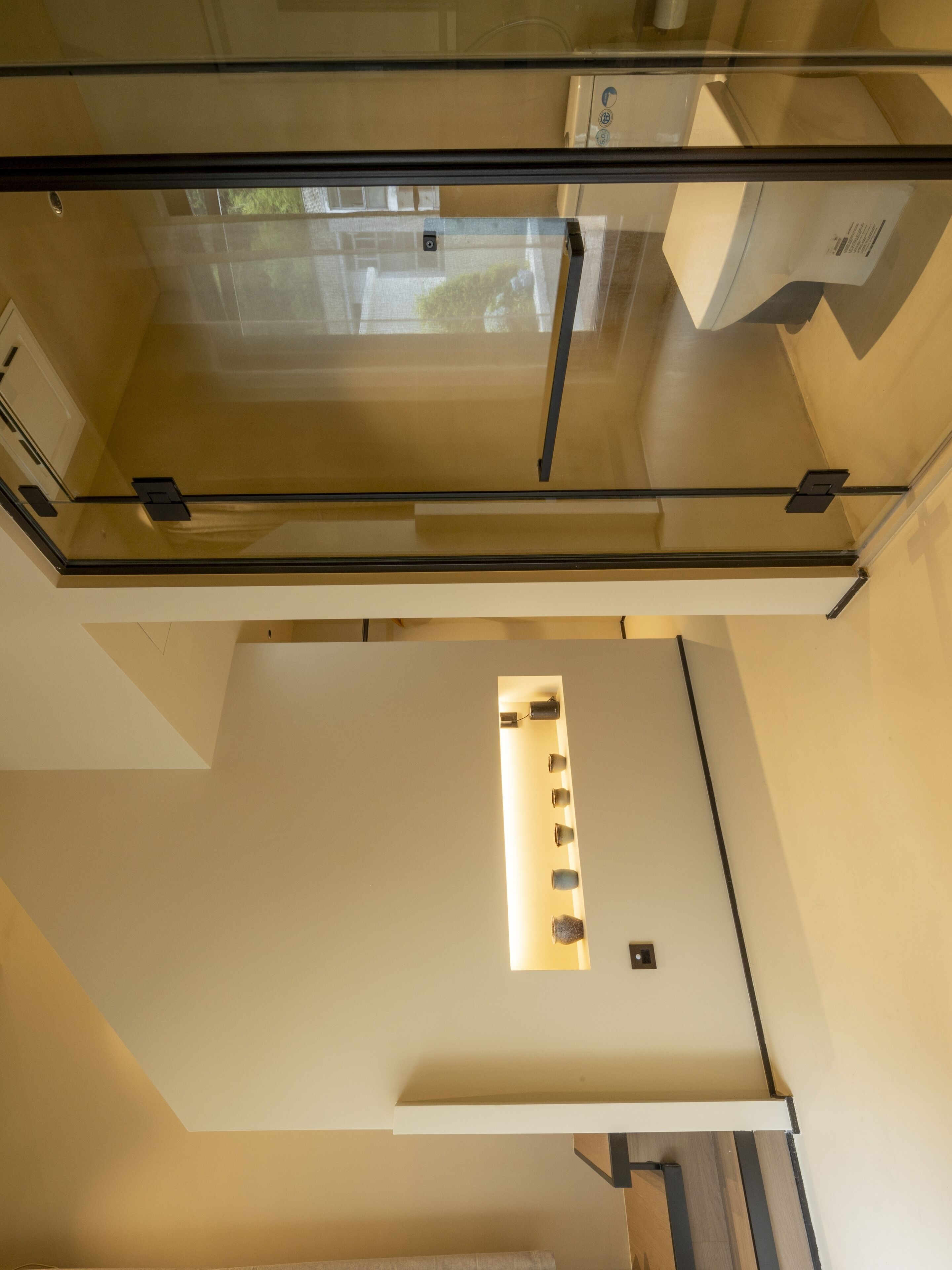 Ein modernes Interieur mit Glastrennwand, einer Treppe und einer Wandleuchte.