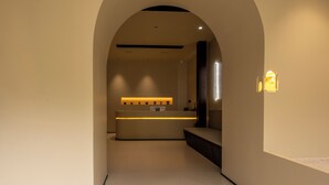 Un interior moderno con una recepción, un banco y un aplique de pared.