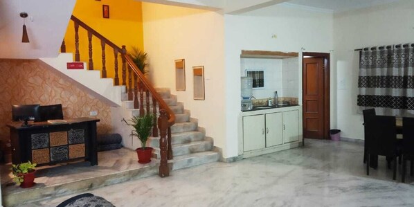 Amplia sala de estar con una escalera, una cocina y un comedor.