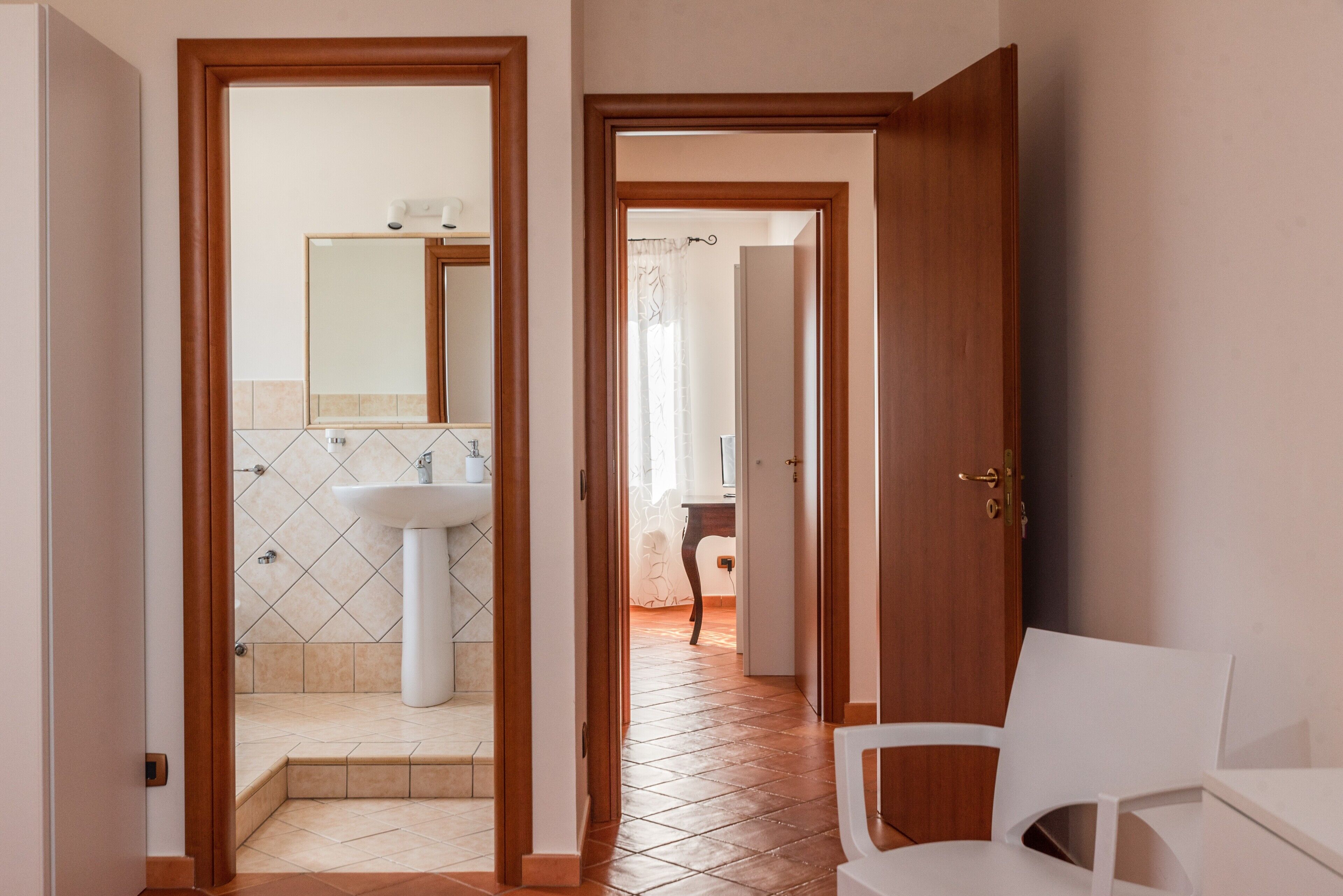 A hallway leading to a bathroom with a sink and mirror.