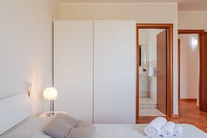 A hotel room with a bed, a bedside lamp, a wardrobe, and a bathroom visible through an open door.