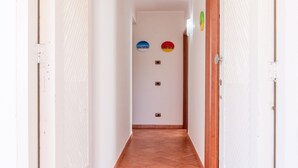 A narrow hallway with white walls, a tiled floor, and two doors on either side.