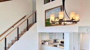 Et moderne interiør med trappe, spiseplads og opholdstue med lædersofa.
