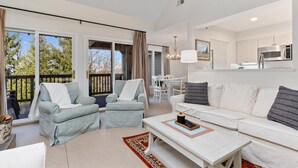 A modern living room with a sofa, armchairs, a coffee table, and a dining area.