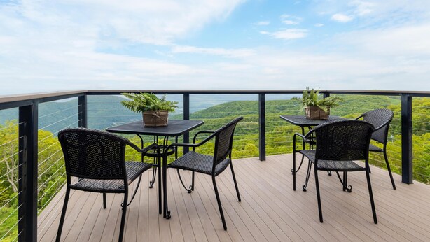 A balcony with a table and chairs, overlooking a scenic view.