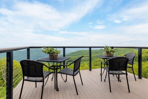 A balcony with a table and chairs, overlooking a scenic view.