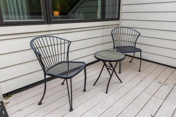 A deck with two metal chairs and a small table.