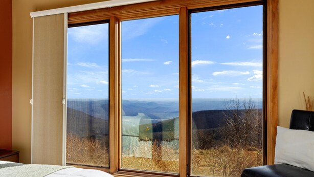 A bedroom with a large window offering a view of a mountainous landscape.