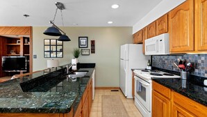 A modern kitchen with wooden cabinets, a granite countertop, a built-in oven, and a microwave.