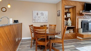 Un comedor con mesa y sillas de madera, una encimera de cocina y una chimenea.