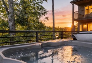 Un bain à remous avec un verre de vin sur un balcon donnant sur une source d’eau chaude.