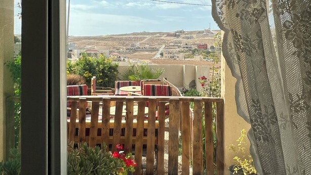 A balcony with a wooden fence, potted plants, and a hanging light fixture. - b&b petrafarmhouse  (Wadi Musa)