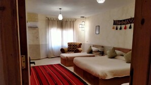 A hotel room with two beds, a red striped rug, a wooden chair, and a ceiling light. - b&b petrafarmhouse  (Wadi Musa)