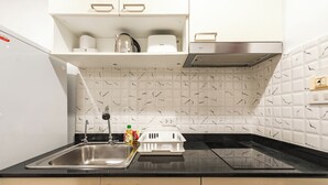 Una cocina moderna con encimera negra, pileta de acero inoxidable y muebles blancos.