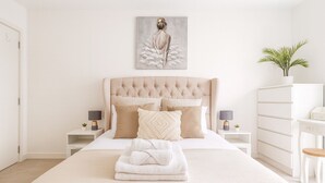 A bedroom with a large bed, two bedside tables with lamps, a dresser, and a wall-mounted painting. - Modern 2-Bed flat in Mill hill Park (London)