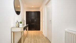 A hallway with a mirrored vanity, dark cabinets, and a radiator. - Modern 2-Bed flat in Mill hill Park (London)