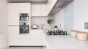 A modern kitchen with white cabinetry, built-in ovens, a gas stove, and a sleek countertop. - Modern 2-Bed flat in Mill hill Park (London)