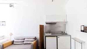A compact room with a bed, a small kitchenette, and a desk. - Eupnea | Studio Apartment, Art by PraXis Apartments (Limassol)