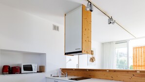 Una cocina moderna con armarios blancos, encimera de madera, un lavamanos y un taburete de madera.