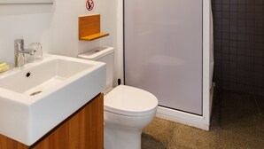 A modern bathroom with a white sink, a toilet, and a shower area. - Euphonia | One-Bedroom Apartment, Art by PraXis Apartments (Limassol)