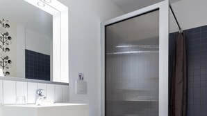 A bathroom with a white sink, toilet, and shower enclosure.