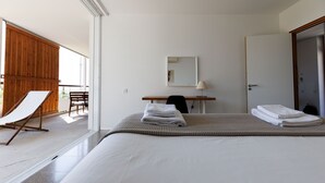 A hotel room with a large bed, a desk, a chair, a mirror, and a sliding door.