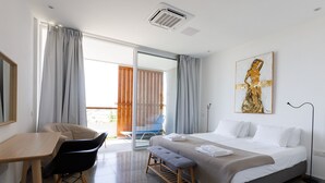 Une chambre d’hôtel avec un lit, un bureau, une chaise, un banc, un tableau et une vue sur l’extérieur.