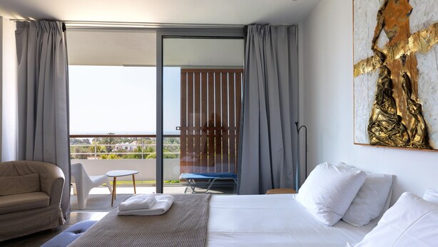 Une chambre d’hôtel avec un lit, un canapé, une chaise et un balcon offrant une vue.