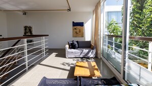Een moderne woonkamer met een bank, een houten salontafel en een groot raam met uitzicht op groen.