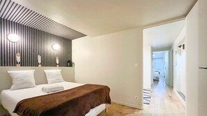 Ein modernes Schlafzimmer mit einem Bett, einem Holzschrankgitter als Kopfteil und einem Flur, der in einen anderen Raum führt.