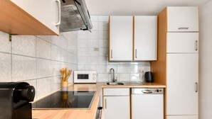 A modern kitchen with a microwave, coffee machine, sink, and dishwasher. - Gartenferienwohnung Arlberg (Bludenz)